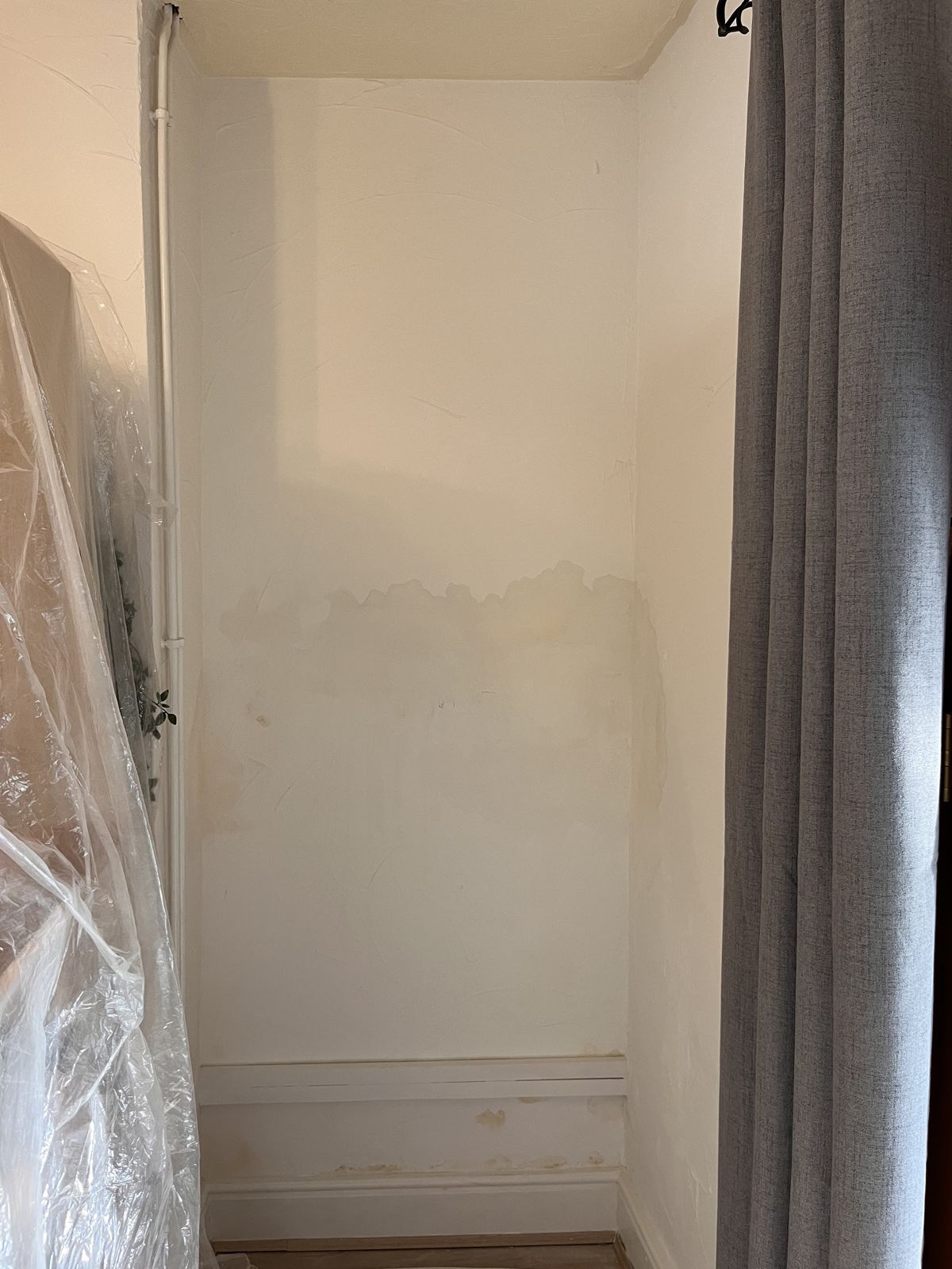 A white wall with a brown damp tide mark above the skirting board