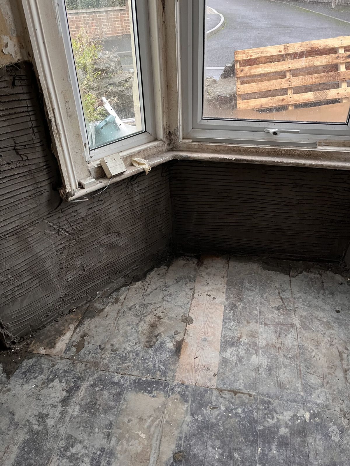 A bay window with the walls below it in fresh scratch-coat render
