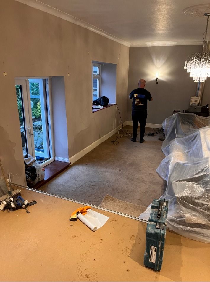 A member of the S&C Preservations team in a branded black T-shirt working in a lounge with the furniture sheeted over